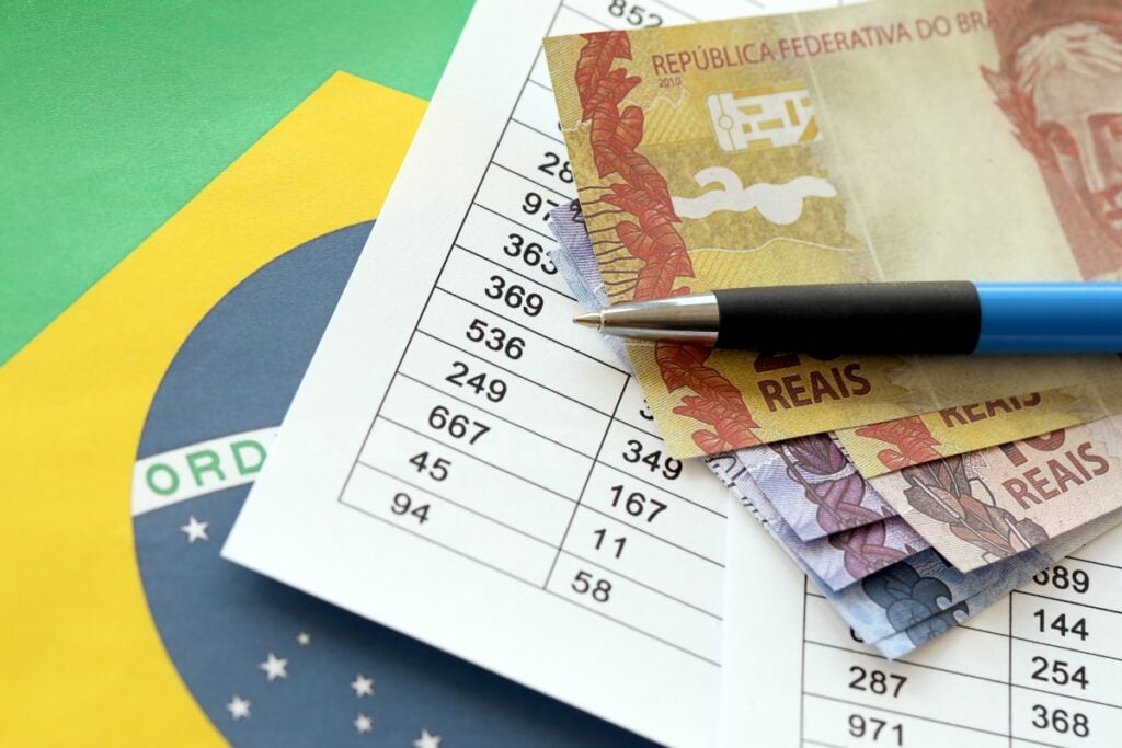 Dinheiro, tabela com informações e bandeira do Brasil. Imagem ilustrativa para texto O que é taxa Selic.